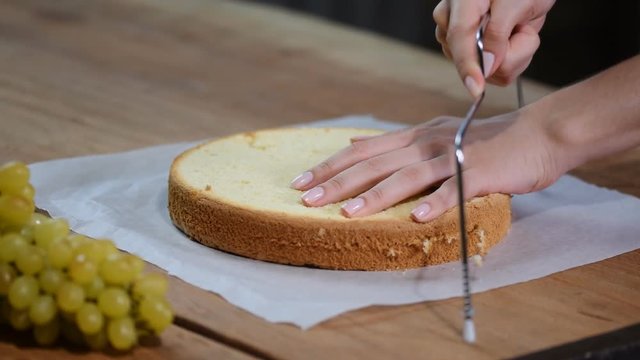 Cutting a confectionery string of sponge cake. Confectionery. Cooking biscuit cake.