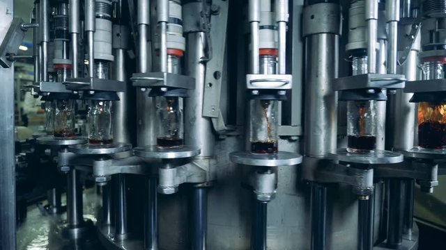 Rotating conveyor and glass bottles getting filled with liquid
