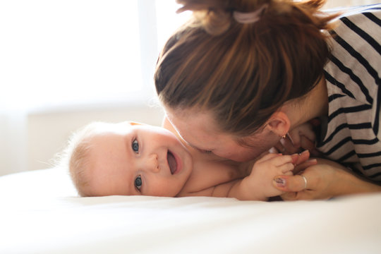 Funny Baby 6 Months Old With Mom On Bed In Room