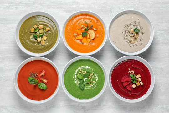 Various soups in bowls on wooden background, top view. Healthy food
