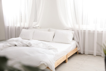 Fototapeta na wymiar Comfortable bed in light room. Interior design