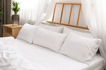 Comfortable bed with soft pillows in room interior