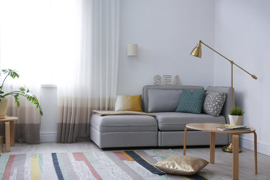 Modern living room interior with comfortable sofa near window