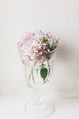Beautiful hydrangea flowers in vintage glass with water on rustic white wood of old windowsill. Countryside still life. Happy mothers day. Creative tender spring image