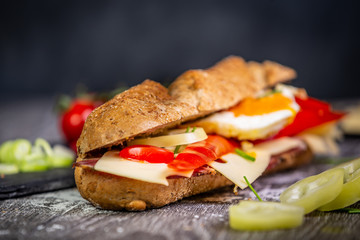 Fresh baguette sandwiches with bacon, cheese, tomatoes on wooden background