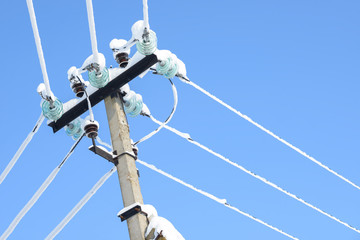 Electric communications wires covered with ice and snow. Snow-covered power cable lines and pole....