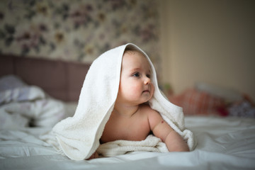Fototapeta na wymiar baby in towel is lying on his stomach on bed
