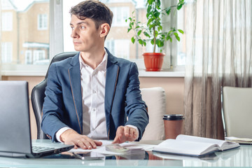 Fototapeta premium Businessman official sitting in the office hides a bribe unnoticed in his pocket. Corruption and bribery