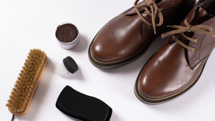 Footwear Concepts and Ideas. Care for leather shoes. Brown man's shoes, Cleaning accessories, brush, cream and spray on white background.