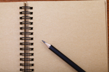 Notepad or notebook with pencil on brown wood table background.using wallpaper for education, business photo