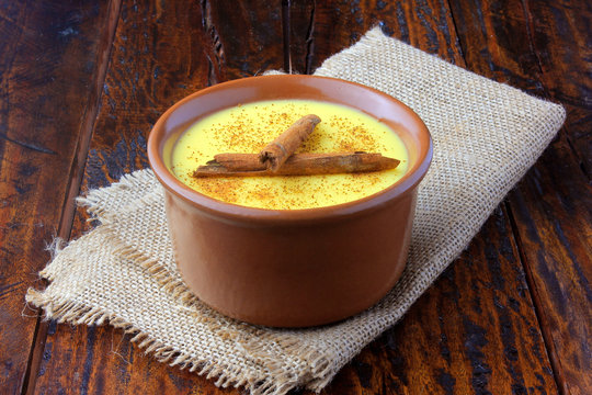 Curau, cream of corn sweet and dessert typical of the Brazilian cuisine, with cinnamon placed in ceramic bowl on wooden table. Copy space