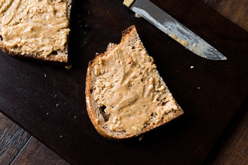 Peanut Butter with Bread and Knife on Wooden Board.