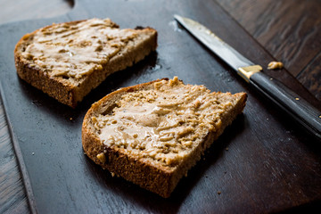 Peanut Butter with Bread and Knife on Wooden Surface.