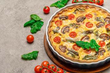 Baked homemade quiche pie in ceramic baking form on concrete background