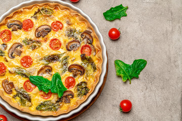 Baked homemade quiche pie in ceramic baking form on concrete background