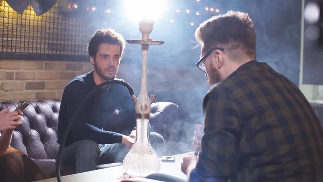 Awesome young people having fun while smoking hookah