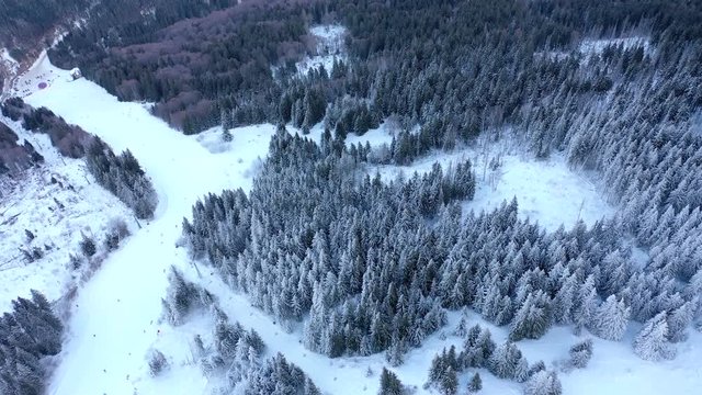 Aerial view skiers and snowboarders on ski lift on snow mountain in ski resort. Ski elevator for people transportation in mountain resort drone view. Winter sport on ski resort.
