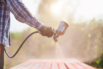 Worker spraying paint to steel pipe to prevent the rust on the surface