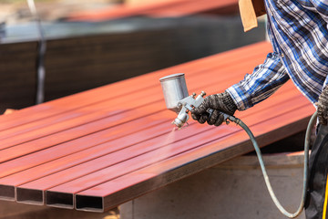 Worker spraying paint to steel pipe to prevent the rust on the surface