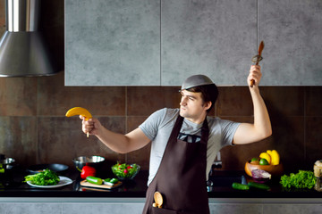 Funny angry loser man male guy with metal sieve, frying pan, wooden kitchen utensils and apron...