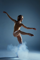 Naklejka premium Dancing in cloud concept. Muscle brunette beauty female girl adult woman dancer athlete in fog smoke fume wearing dance bodysuit making emotional dance element performance on isolated grey background