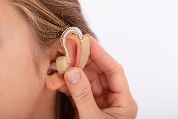 Doctor Inserting Hearing Aid In Girl's Ear