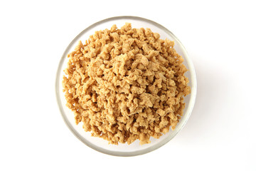 Raw soy mince in glass bowl isolated on white background. Dry soya mince meat. top view
