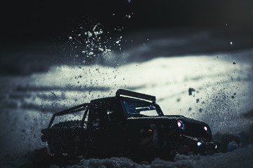 Radio-controlled car in the snow at night, lights shine. Christmas entertainment gift rc car - obrazy, fototapety, plakaty