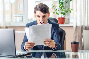 Male businessman sitting at a work place examing documents. Concept of the office working with documents