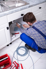 Plumber Cleaning Clogged Sink Pipe
