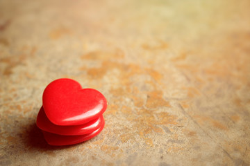 Love for Valentine's day: three red beads with a shape of a heart on brown floor