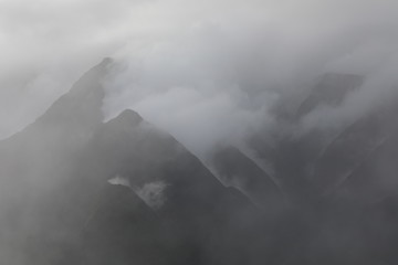 Several mountains stand in the fog