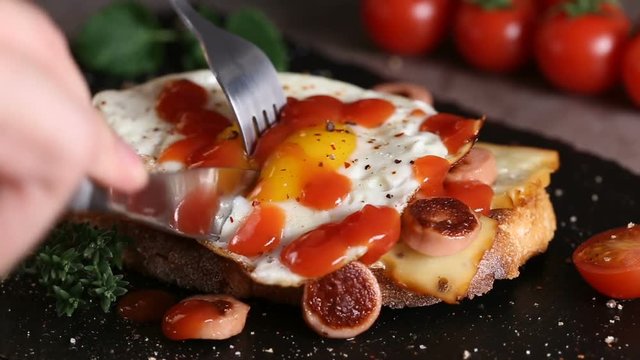 Eating open sandwich made with egg, cheese and sausages from slate