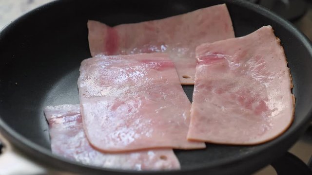 Cooking fried bacon on frying pan, closeup