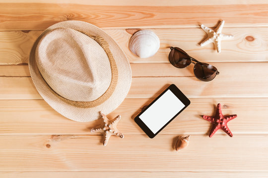 Hat, sunglasses, smartphone, starfishes and seashells on wooden background. Toned image.
