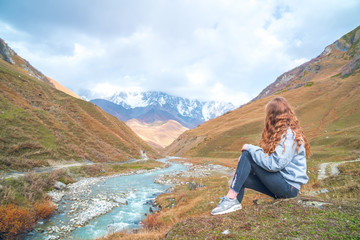 Naklejka na ściany i meble Beautiful girl on a mountain background of Svaneti, mountain Shkhara, relax while traveling.
