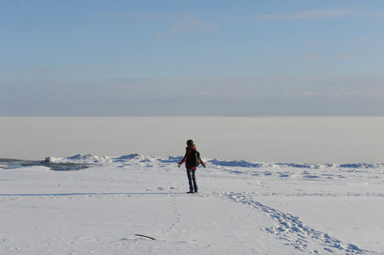 Winter snowy coastal landscape on a sunny day. Frozen river. Clear sky. Open space. The figure of single traveler