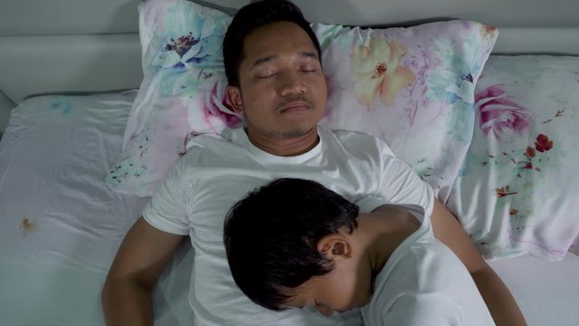 Young father and his little boy sleeping on bed in bedroom at home. Shot in 4k resolution