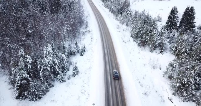 Aerial view fly over the highway winter road among the snowy forest.