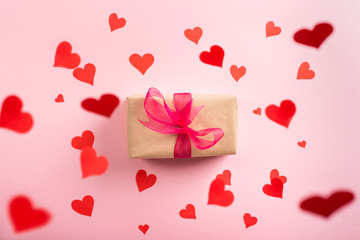 Hearts flying down to gift box with pink ribbon, top view