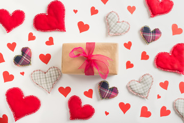 Gift box with paper and textile hearts scattered around, top view
