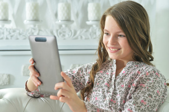 Portrait of little girl in pajama using digital tablet at home