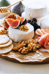 Camembert cheese, figs, jamon, honey and grapes. Cheese plate on marble background