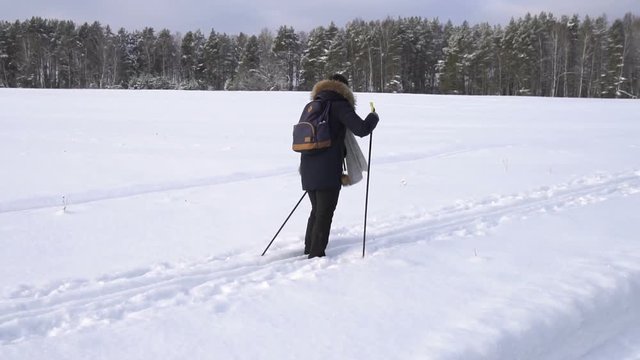 Woman with a backpack skiing in countryside in snowy russian winter. Slow motion
