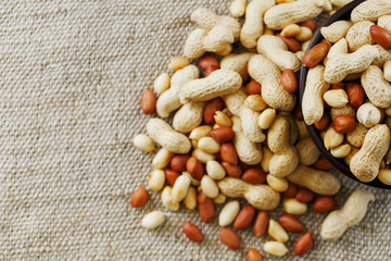 Peanuts in the shell and peeled close-up in cups. Roasted peanuts in their shells and peeled against a brown cloth.