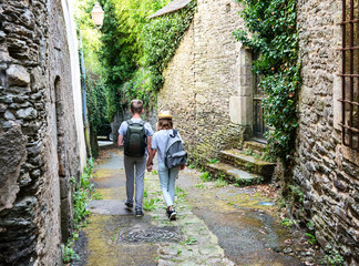 Fototapeta na wymiar Teenagers people and travel concept. Teens walking in the street of an old town, historical centre of the town, Rochefort-en-Terre, France