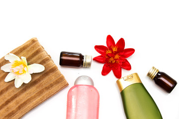 plastic bottle of body care or shampoo above brown  towel, essential oil with white flower isolated on white background, beauty products concept