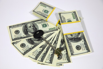 Fototapeta premium Bundles of hundred dollar banknotes on a white background. House keys. The keys to the apartment on the dollars.