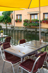 Empty cosy french street cafe or brasserie located on small river with served tables ready for visitors