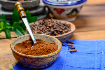 Bowls with dried clove buds and cloves powder, used for cooking and traditional medicine, close up, spices collection